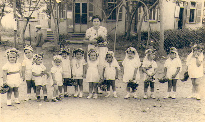 הגננת סטלה צהנר ותלמידיה בדרכם לבית הספר העממי לחגיגת הביכורים, שנות ה-30 (תמ1511)